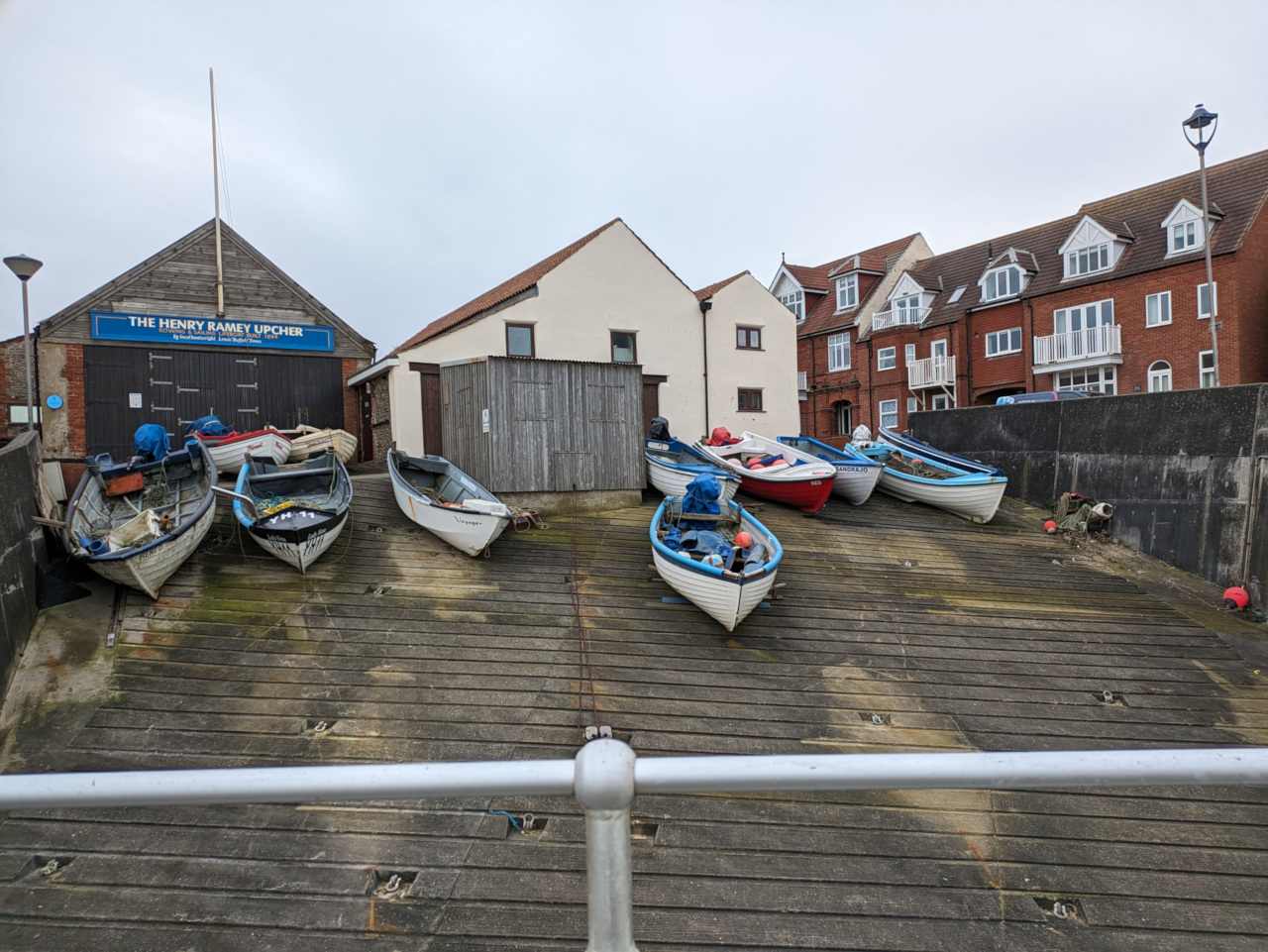 Old boats on launching ramp, in front of buildings.