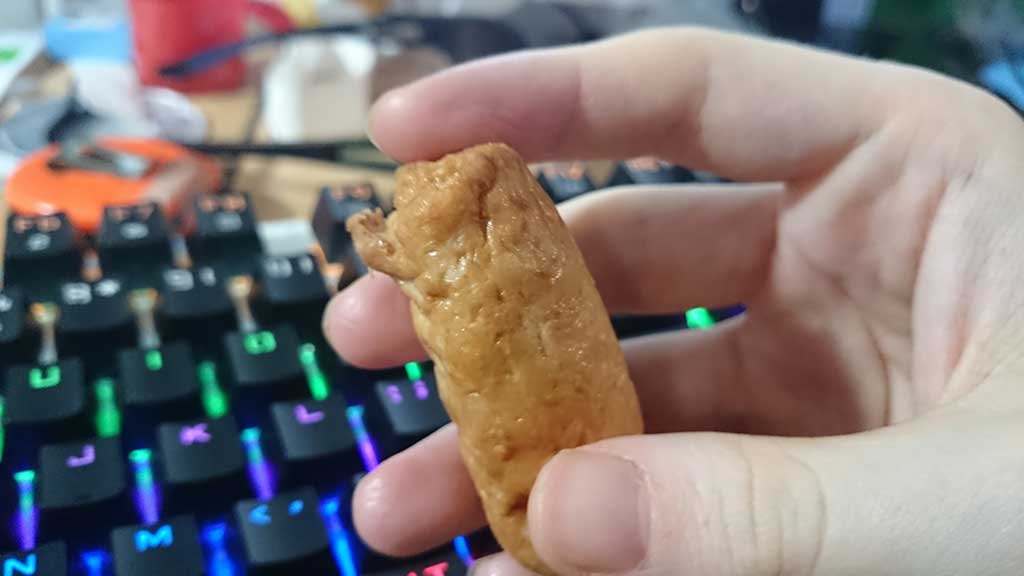 A Quorn Cocktail Sausage being held with my hand, towards camera.