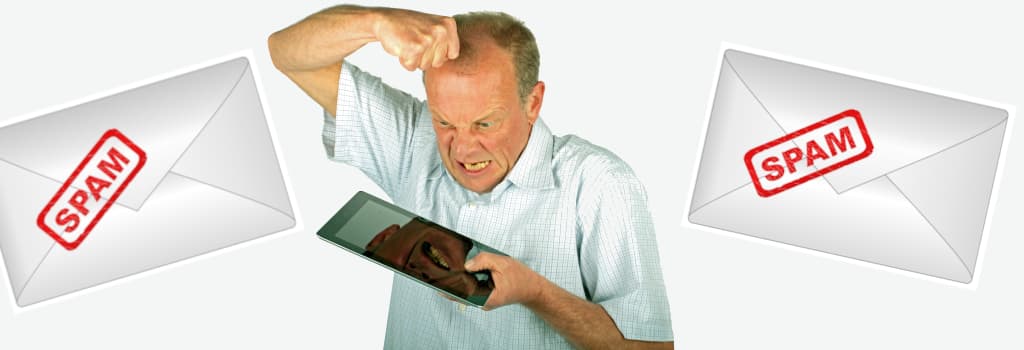 Old man angry at his tablet and two envelopes with &ldquo;spam&rdquo; written on them besides that man.
